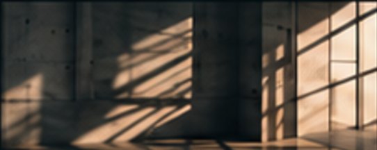 Late light falling through a tall window grid onto a bare concrete wall